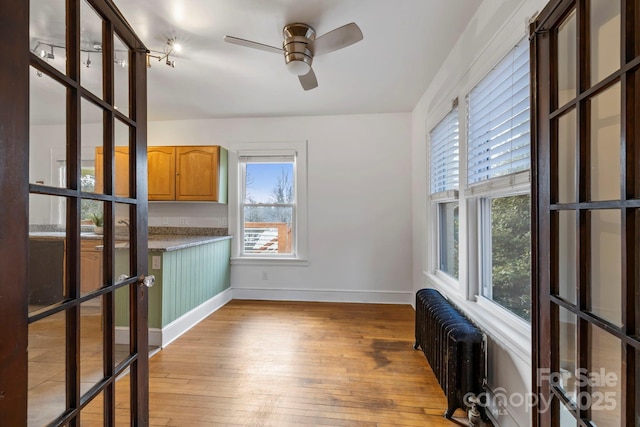 unfurnished dining area featuring radiator, ceiling fan, and light hardwood / wood-style flooring