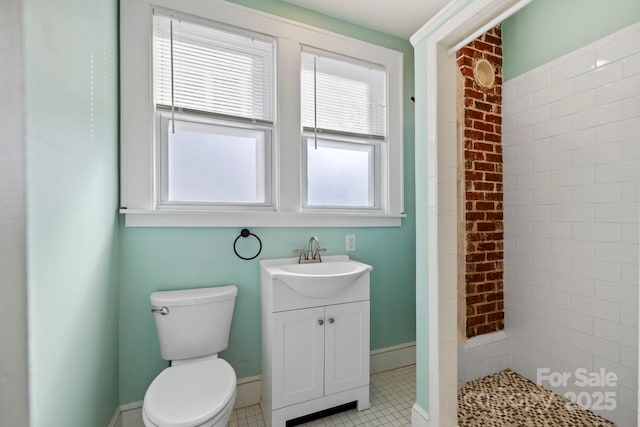 bathroom with vanity, tile patterned floors, toilet, and tiled shower