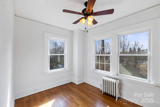 unfurnished room with radiator, a wealth of natural light, and dark hardwood / wood-style floors