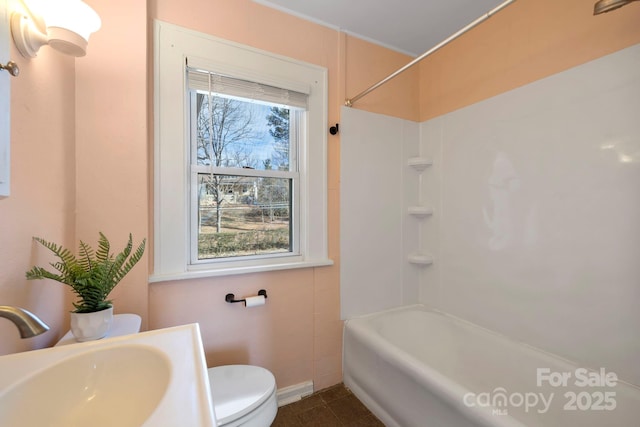 full bathroom with washtub / shower combination, tile patterned floors, toilet, and sink