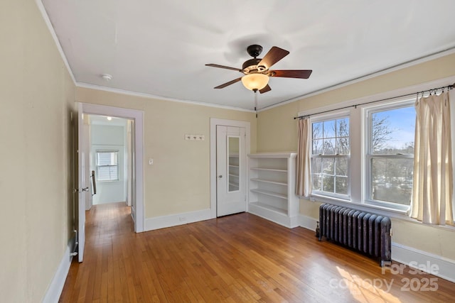 spare room featuring crown molding, hardwood / wood-style flooring, radiator heating unit, and ceiling fan