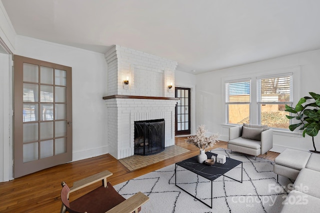 living room with a fireplace, crown molding, and wood-type flooring