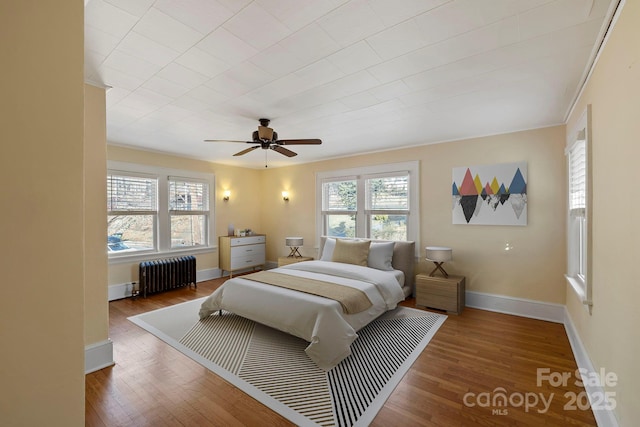 bedroom featuring ceiling fan, radiator heating unit, and wood-type flooring