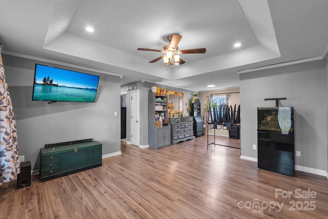 unfurnished living room with a tray ceiling, light hardwood / wood-style floors, and a textured ceiling