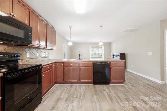 kitchen with tasteful backsplash, a peninsula, light countertops, black appliances, and a sink