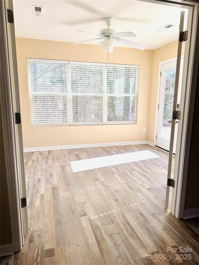 empty room featuring visible vents, light wood-style flooring, and baseboards