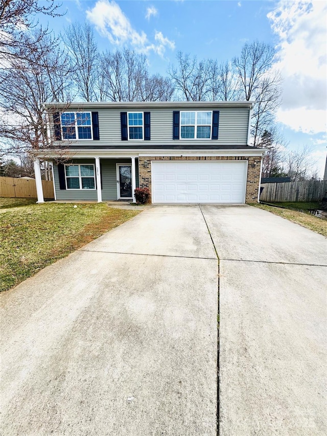 traditional-style house with an attached garage, fence, a front lawn, and concrete driveway