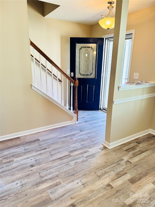 entrance foyer with wood finished floors, baseboards, and stairs