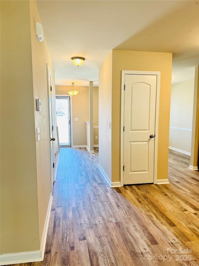 hallway featuring baseboards and light wood finished floors