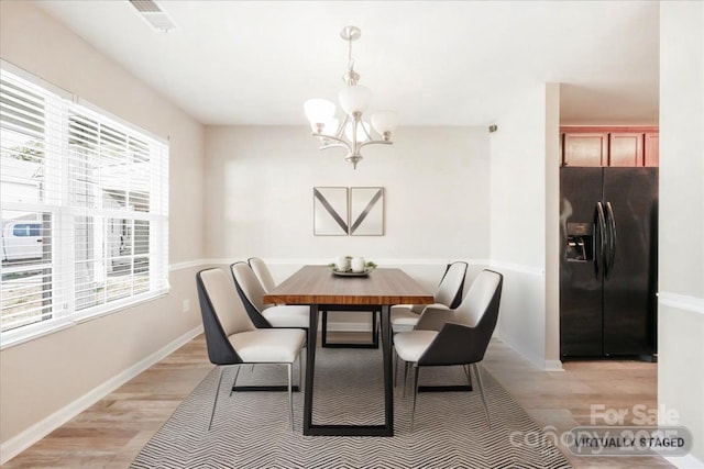 dining room with light wood finished floors, visible vents, baseboards, and an inviting chandelier