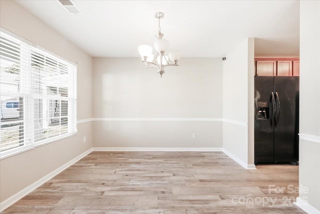 unfurnished dining area featuring light wood finished floors, visible vents, baseboards, and a notable chandelier