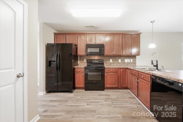 kitchen featuring black appliances, light wood finished floors, backsplash, and a sink