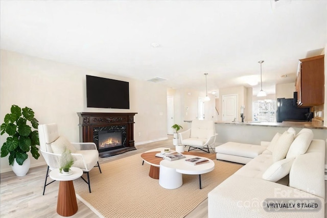 living room featuring light wood-type flooring, a fireplace with flush hearth, and baseboards