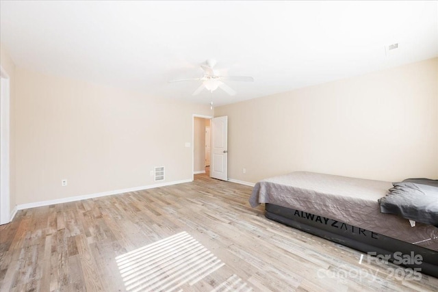 unfurnished bedroom featuring a ceiling fan, baseboards, visible vents, and wood finished floors