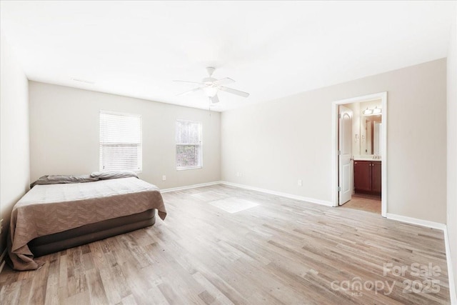 bedroom with light wood-type flooring, ceiling fan, ensuite bath, and baseboards