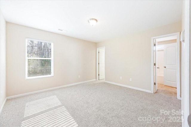 spare room with light carpet and baseboards