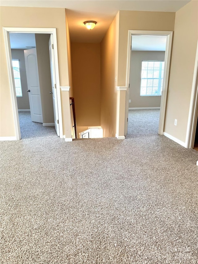 carpeted spare room featuring a healthy amount of sunlight and baseboards