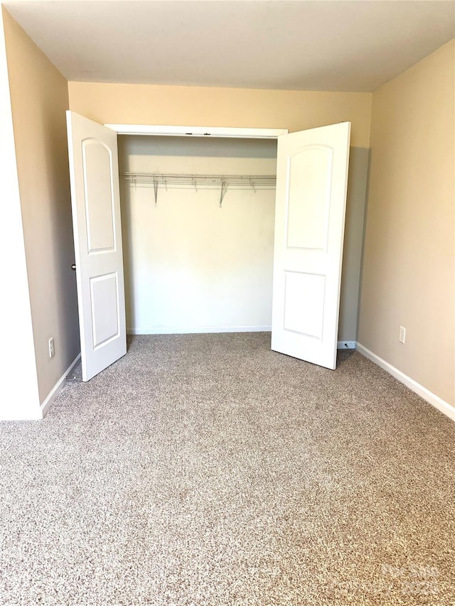 unfurnished bedroom with a closet, carpet, and baseboards