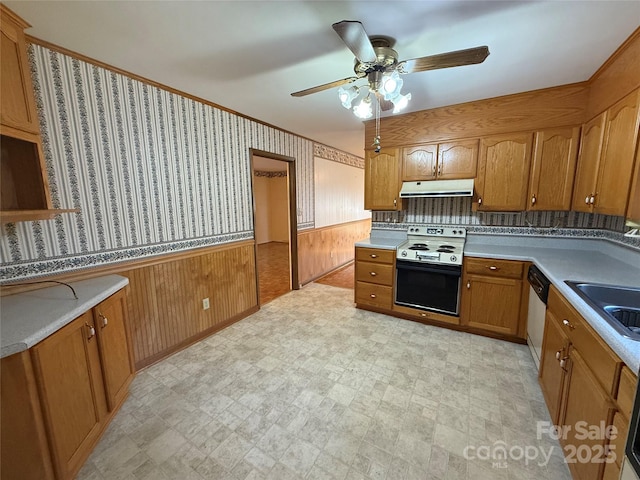 kitchen with sink, range with electric stovetop, stainless steel dishwasher, wooden walls, and ceiling fan