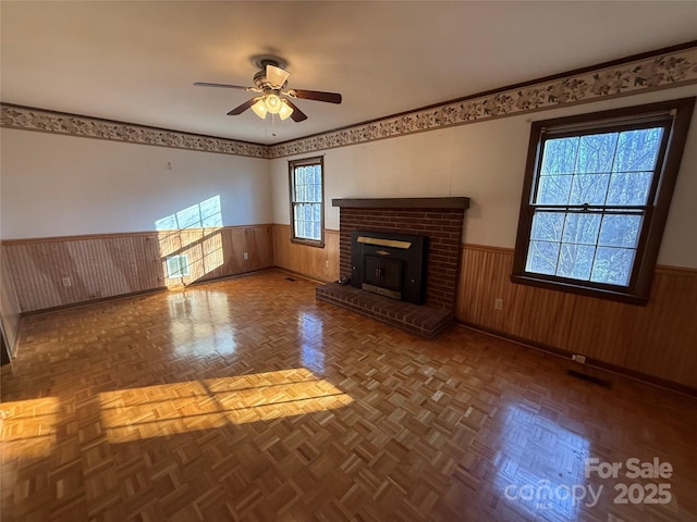 unfurnished living room featuring parquet flooring, ceiling fan, and wood walls