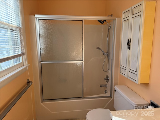 bathroom featuring enclosed tub / shower combo, plenty of natural light, and toilet