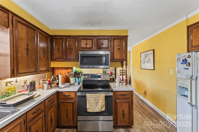 kitchen featuring crown molding, stainless steel appliances, light hardwood / wood-style floors, and a textured ceiling