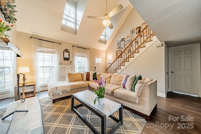 living room with a skylight, dark wood-type flooring, high vaulted ceiling, and ceiling fan