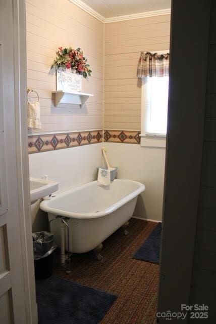 bathroom featuring crown molding, hardwood / wood-style floors, and a tub