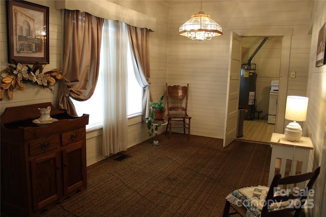 sitting room with gas water heater, a chandelier, and wood walls