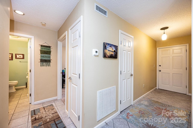 corridor with a textured ceiling and light tile patterned floors