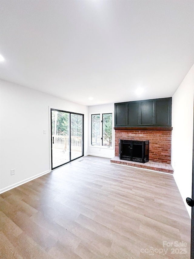 unfurnished living room featuring a fireplace and light hardwood / wood-style floors