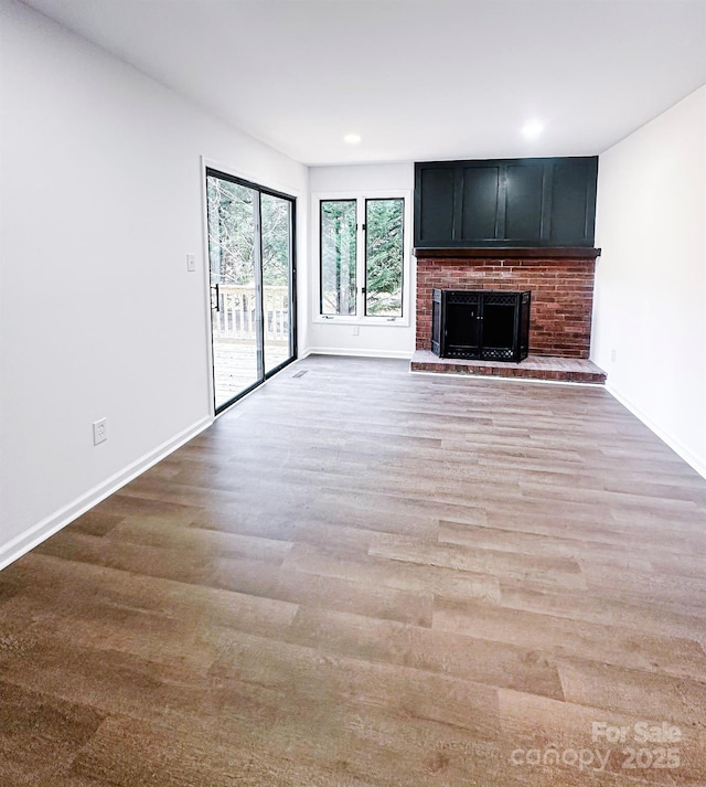 unfurnished living room featuring a brick fireplace and light hardwood / wood-style flooring