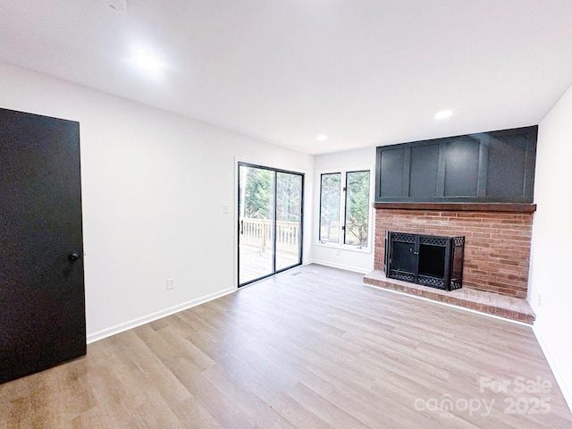 unfurnished living room featuring a brick fireplace and light hardwood / wood-style floors