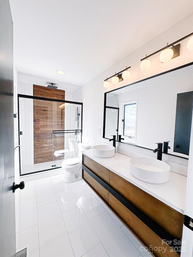 bathroom with tile patterned flooring, vanity, tiled shower, and toilet