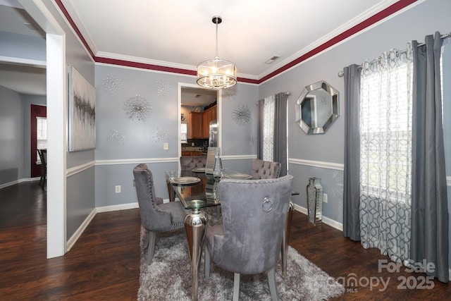 dining room with crown molding, dark hardwood / wood-style floors, and an inviting chandelier