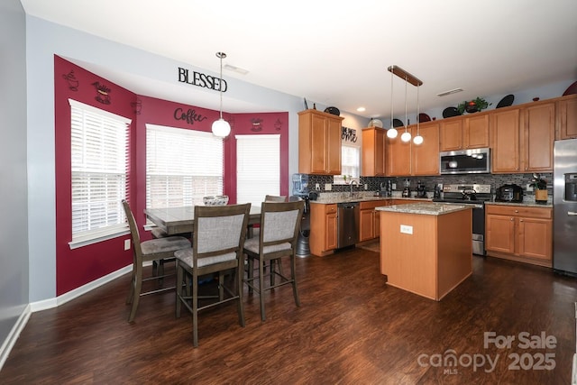 kitchen with decorative light fixtures, dark wood-type flooring, stainless steel appliances, and a kitchen island