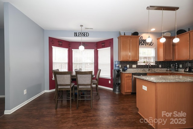 kitchen featuring sink, light stone counters, decorative light fixtures, dishwasher, and backsplash