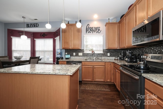 kitchen with light stone counters, sink, a kitchen island, and appliances with stainless steel finishes