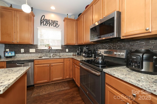 kitchen with dark wood-type flooring, appliances with stainless steel finishes, light stone countertops, and sink