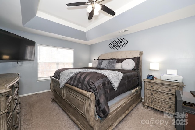 bedroom featuring a raised ceiling, dark carpet, and ceiling fan