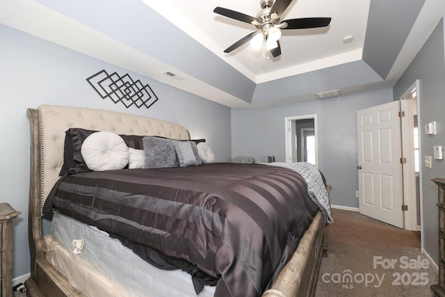 carpeted bedroom featuring ceiling fan and a tray ceiling