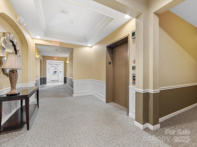 hall featuring a raised ceiling, crown molding, light carpet, and elevator