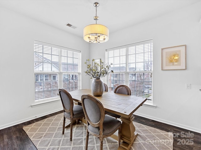 dining area with dark hardwood / wood-style flooring and an inviting chandelier