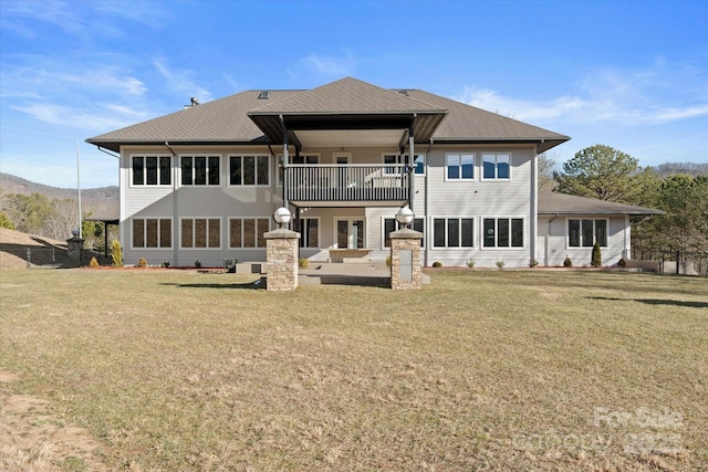 back of property featuring a balcony and a yard