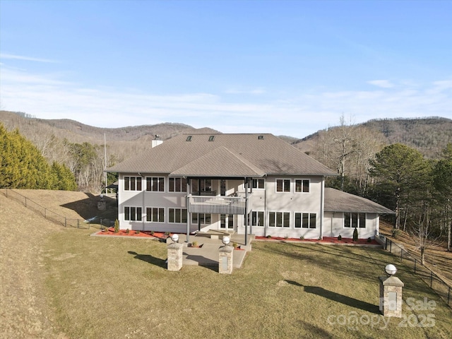 rear view of house featuring a balcony, a yard, a mountain view, and a patio