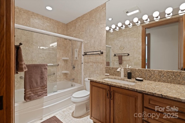 full bathroom with bath / shower combo with glass door, tile walls, vanity, and toilet