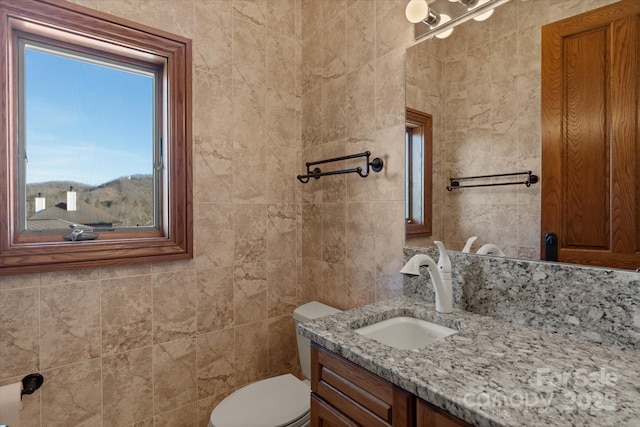 bathroom with vanity, tile walls, and toilet