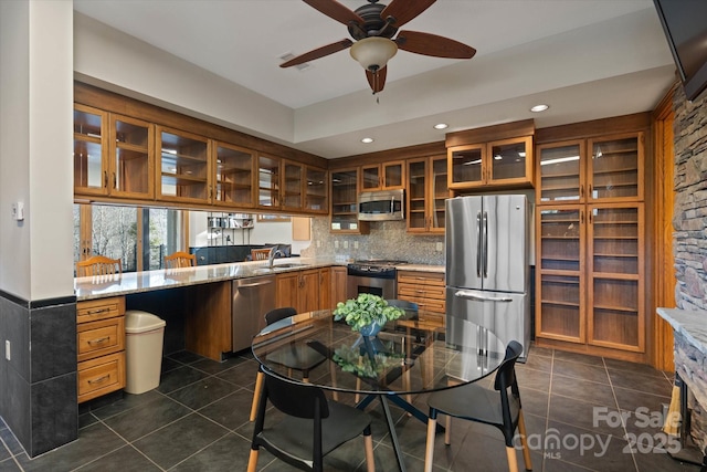 kitchen featuring sink, dark tile patterned floors, light stone counters, kitchen peninsula, and stainless steel appliances