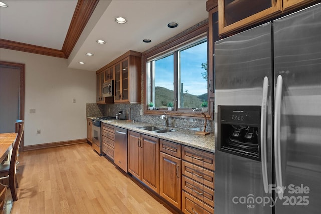 kitchen featuring sink, decorative backsplash, light stone counters, stainless steel appliances, and crown molding