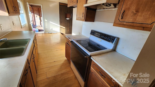 kitchen with ventilation hood, sink, light wood-type flooring, and electric stove